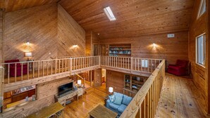A spacious wooden cabin with a loft bedroom, a dining area, and a living room with a fireplace. - Snail’s Pace South-6br/3.5 bath w/gorgeous views (Fort Payne)