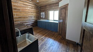 A kitchen with wooden walls, a window, and a sink. - Remote Cabin near Warm River (Ashton)