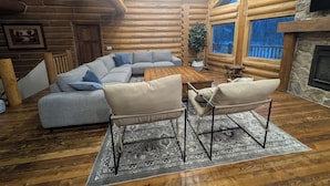 A log cabin interior with a sectional sofa, two armchairs, a coffee table, and a fireplace. - Remote Cabin near Warm River (Ashton)