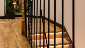 Eine Holztreppe mit schwarzen Geländern und einer grünen Wand oben.