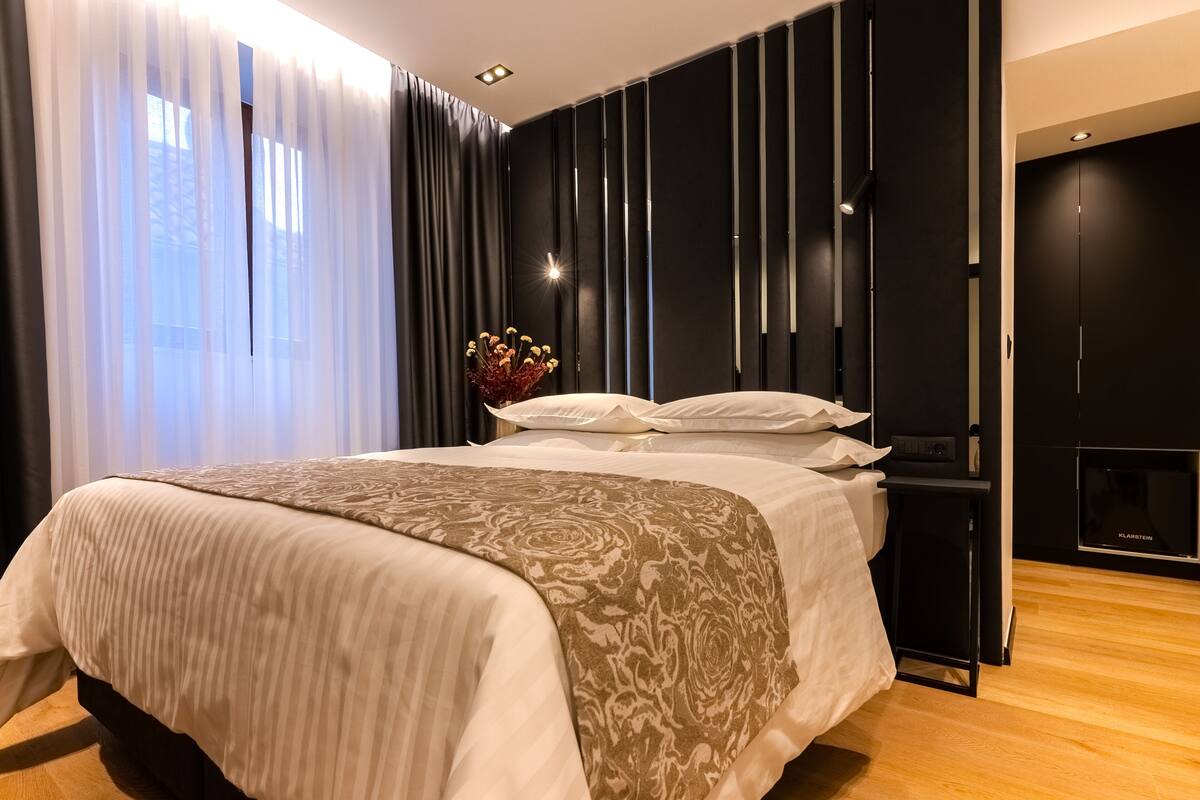 Une chambre d’hôtel moderne avec un grand lit, une table de chevet et un petit téléviseur.