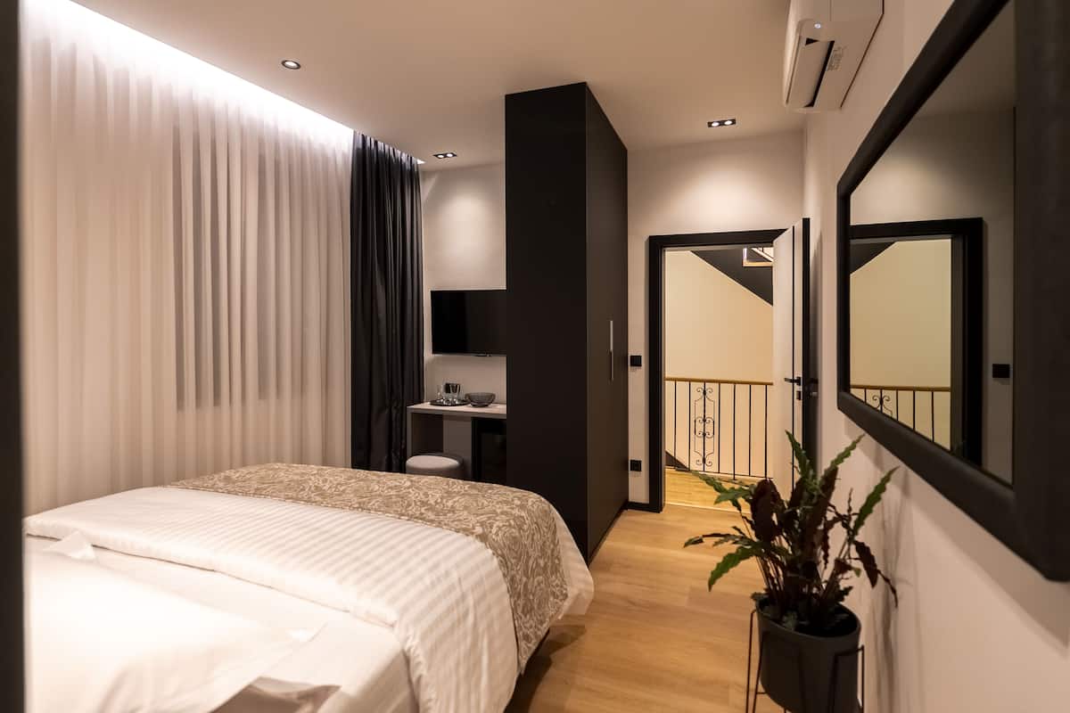 Une chambre moderne avec un grand lit, une table de chevet, un miroir et une plante en pot.