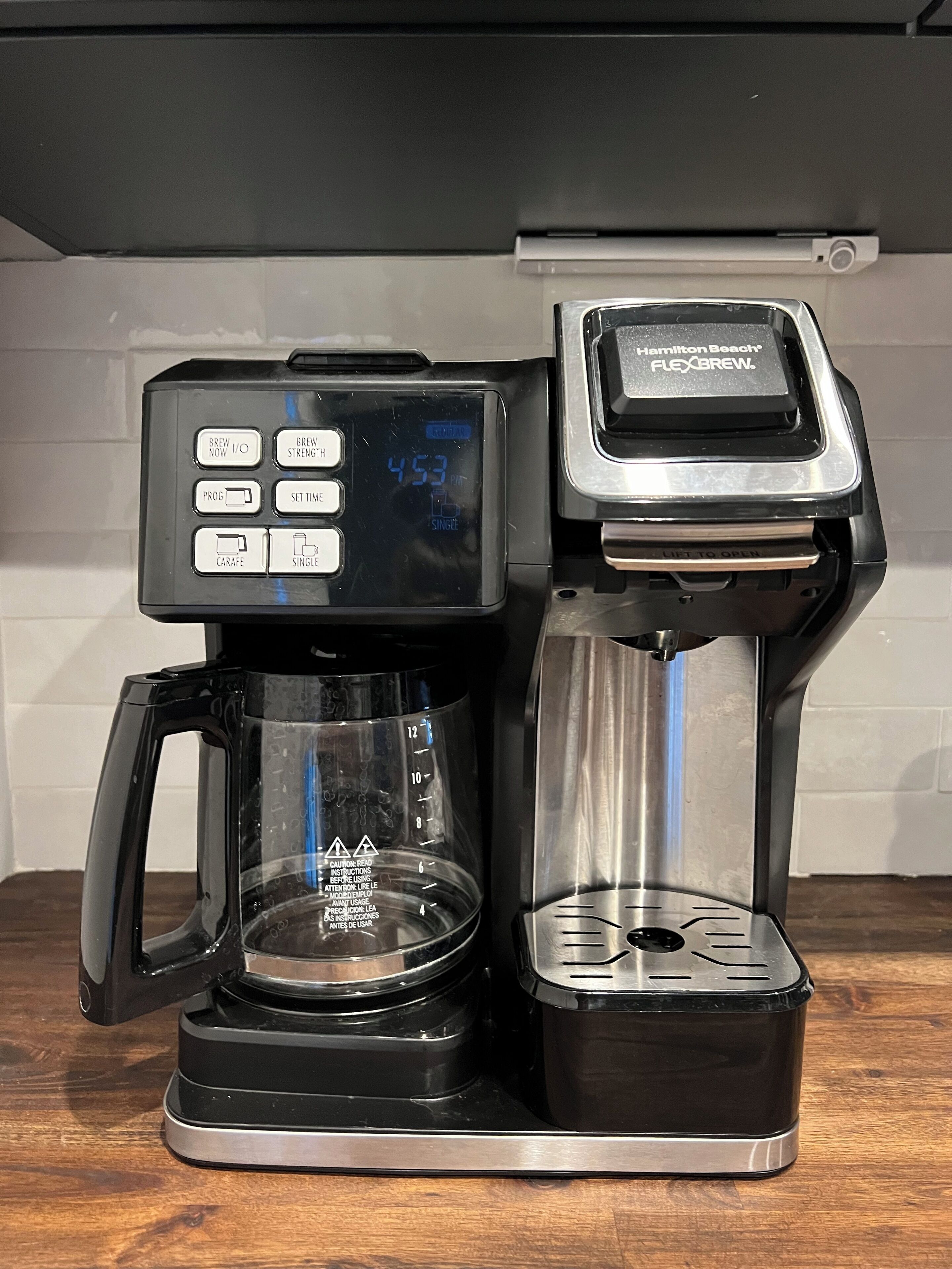 Eine Hamilton Beach FlexBrew Kaffeemaschine mit digitaler Anzeige, einer Kaffeekanne und einem Halter für Einzelportions-Kapseln.