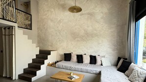 A modern living room with a sofa, a coffee table, and a staircase. - Stella's Loft In Center Of Tinos (Tinos)