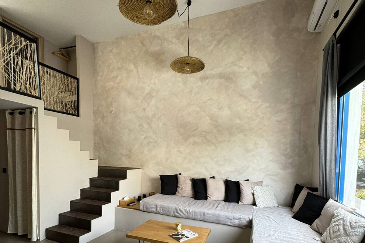 A modern living room with a sofa, a coffee table, and a staircase.