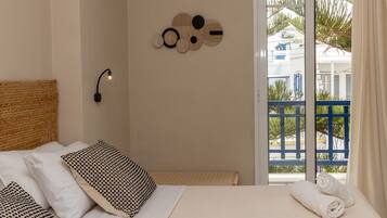 Una camera da letto con un letto, cuscini, un quadro e vista su un balcone blu.