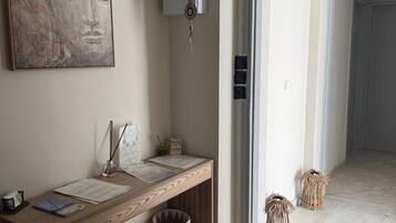 Un pasillo con una consola de madera, una lámpara de pared, una obra de arte enmarcada y una puerta que da a otra habitación.