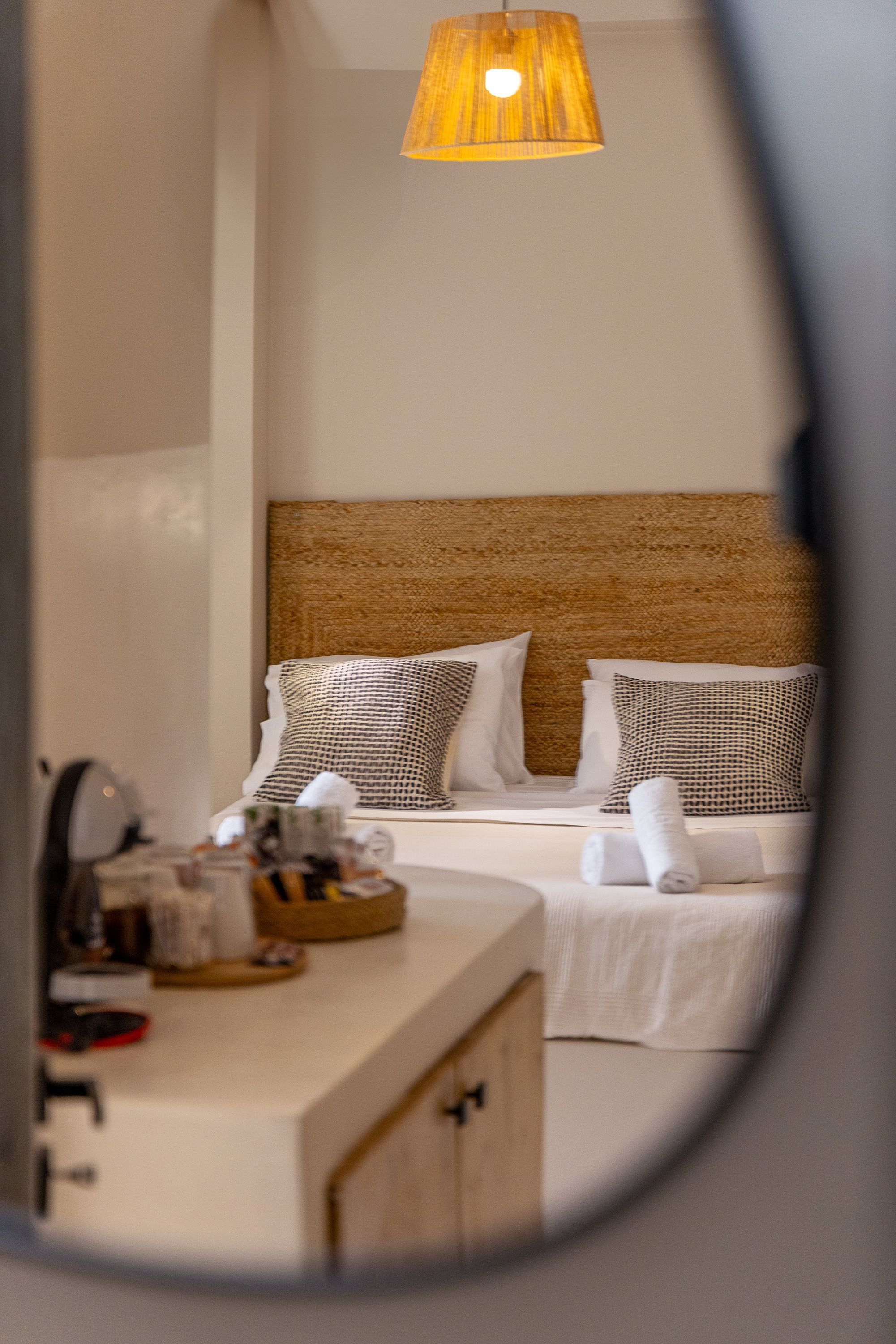 Une chambre à coucher avec un lit, des oreillers, une table de chevet et un miroir.