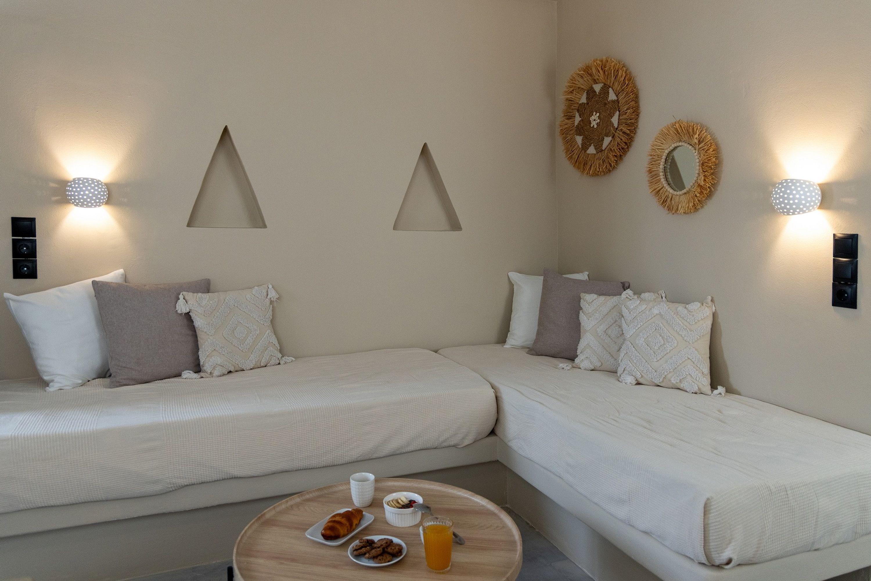 Una habitación con dos camas, una mesita redonda con provisiones para el desayuno, y lámparas fijadas a la pared.