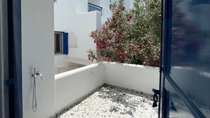 A small, enclosed balcony with a white tiled floor and a shower area. - Zen Beach House in Tinos 2 (Tinos)