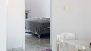 Un couloir qui mène à une chambre à coucher, où se trouvent un lit, une petite table et une chaise.