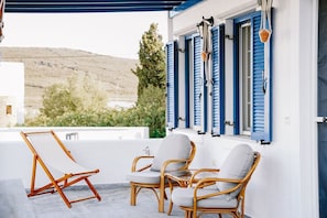 A terrace with wicker chairs and a canvas chair, overlooking a hillside. - Menmar House in Tinos (Tinos)