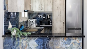 A kitchen with wooden cabinets, a stainless steel refrigerator, a microwave, and a coffee maker. - Zen Beach House in Tinos 1 (Tinos)