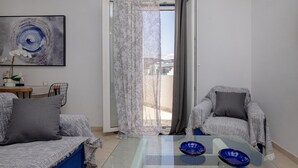 A modern living room with a glass coffee table, two sofas, a chair, and a painting on the wall. - Zen Beach House in Tinos 1 (Tinos)