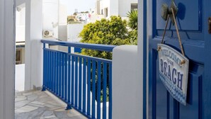 A blue door with a "Welcome to our Beach" sign, a white building, and a stone-paved walkway. - Zen Beach House in Tinos 1 (Tinos)
