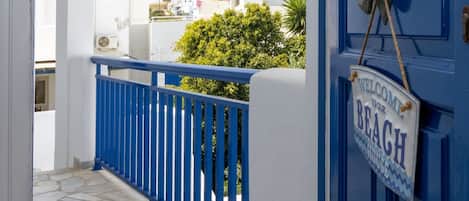 A blue door with a "Welcome to our Beach" sign, a white building, and a stone-paved walkway.