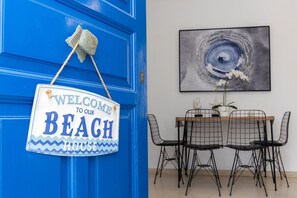 A blue door with a 'Welcome to our Beach House' sign and a dining area with a table and chairs. - Zen Beach House in Tinos 1 (Tinos)