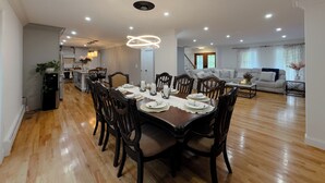 A spacious living area with a dining table set for six, surrounded by dark wooden chairs.