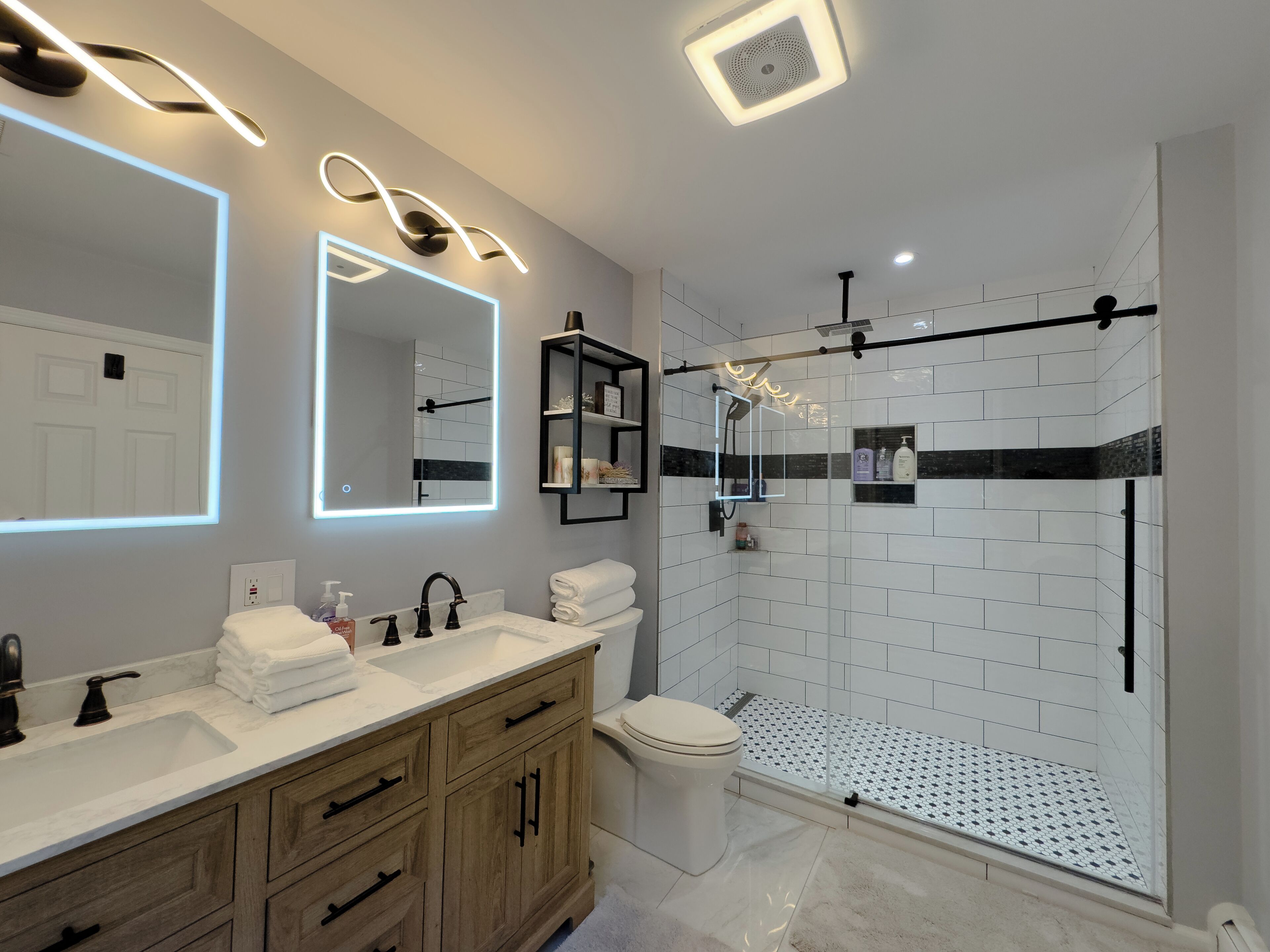 A modern bathroom with a vanity, a toilet, and a walk-in shower.