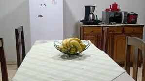 A dining table with a banana bowl, a white refrigerator, and a coffee maker in a kitchen. - House 2 bedrooms from the center of Bonito-MS, rooms with air conditioning (Rincão Bonito Bonito)