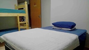 A room with a bunk bed, a single bed with a blue mattress and white bedding, a wooden door, and a tiled floor. - House 2 bedrooms from the center of Bonito-MS, rooms with air conditioning (Rincão Bonito Bonito)