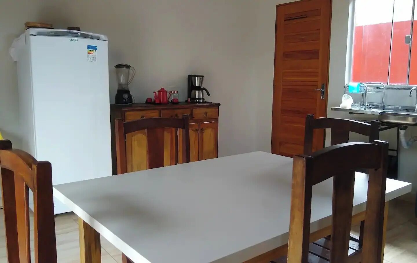 A small kitchen with a white refrigerator, wooden cabinets, a coffee maker, and a sink.