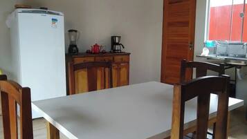 A small kitchen with a white refrigerator, wooden cabinets, a coffee maker, and a sink.