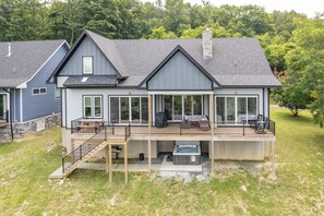 A two-story house with a covered deck, large windows, and a stone chimney.