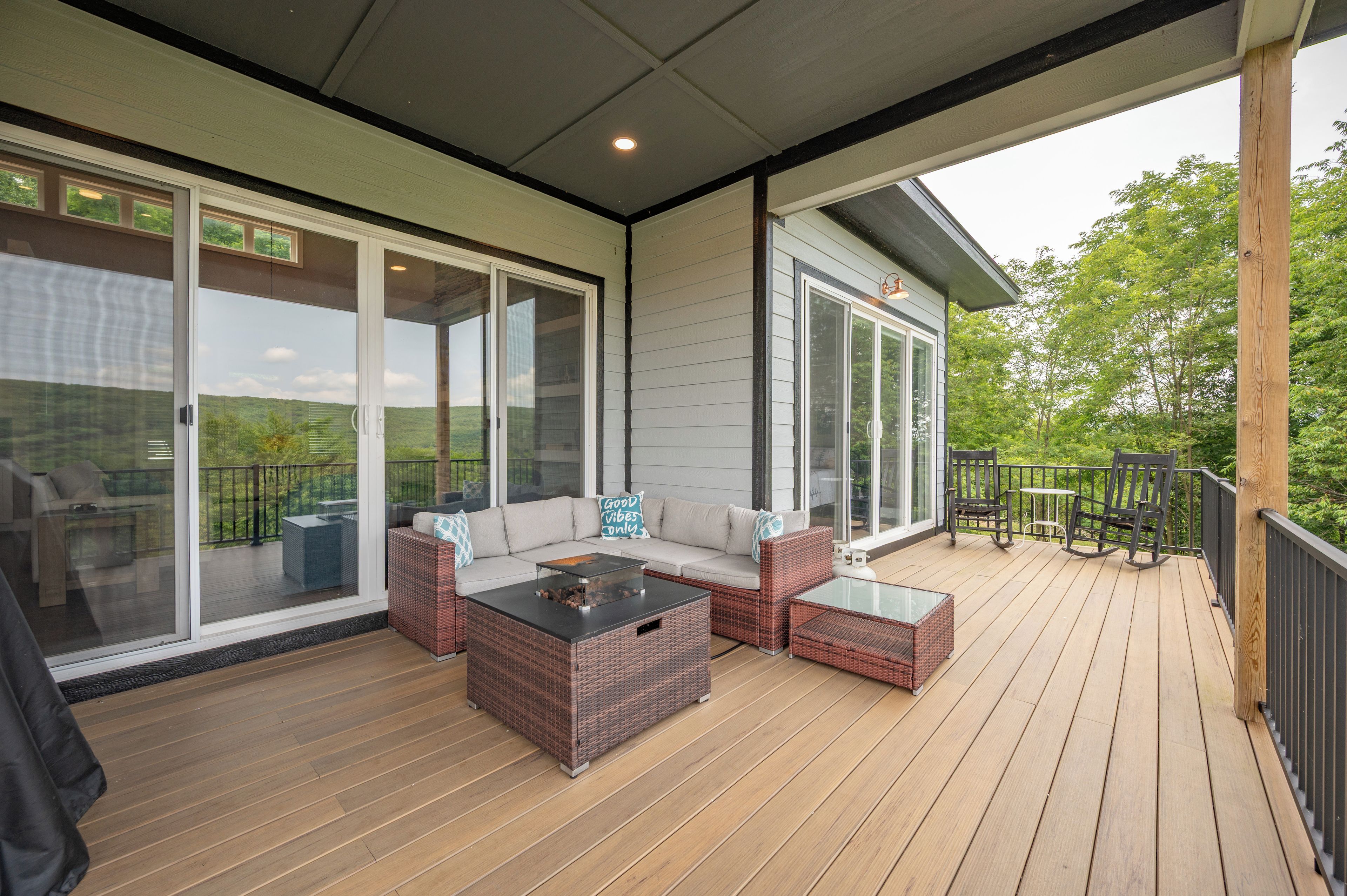 Une terrasse extérieure couverte, aménagée avec un canapé, deux petites tables basses en osier et un coin repas comprenant des chaises et une table.