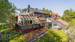 A modern house with a glass conservatory, wooden deck, and a well-maintained garden.