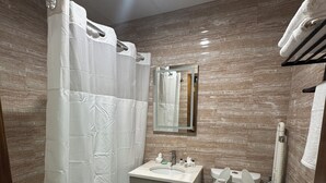 A bathroom with a bathtub, toilet, and sink. - Dream Hotel Bronx (Mount Vernon)