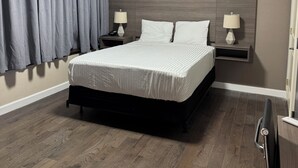 A modern hotel room with a large bed, bedside tables with lamps, a ceiling light, and an air conditioning unit. - Dream Hotel Bronx (Mount Vernon)