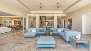 A spacious living area with a light blue sectional sofa, a coffee table, and a modern staircase.
