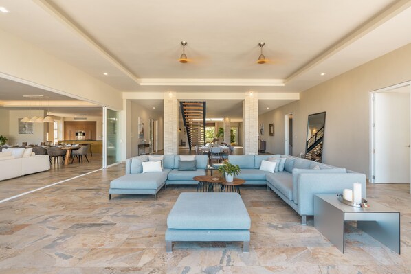 A spacious living area with a light blue sectional sofa, a coffee table, and a modern staircase.