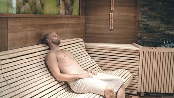 A man lying on a wooden bench with slats, in a room with a stone wall and a wooden panel.