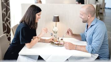 A couple dining at a table with a dessert plate in front of them.