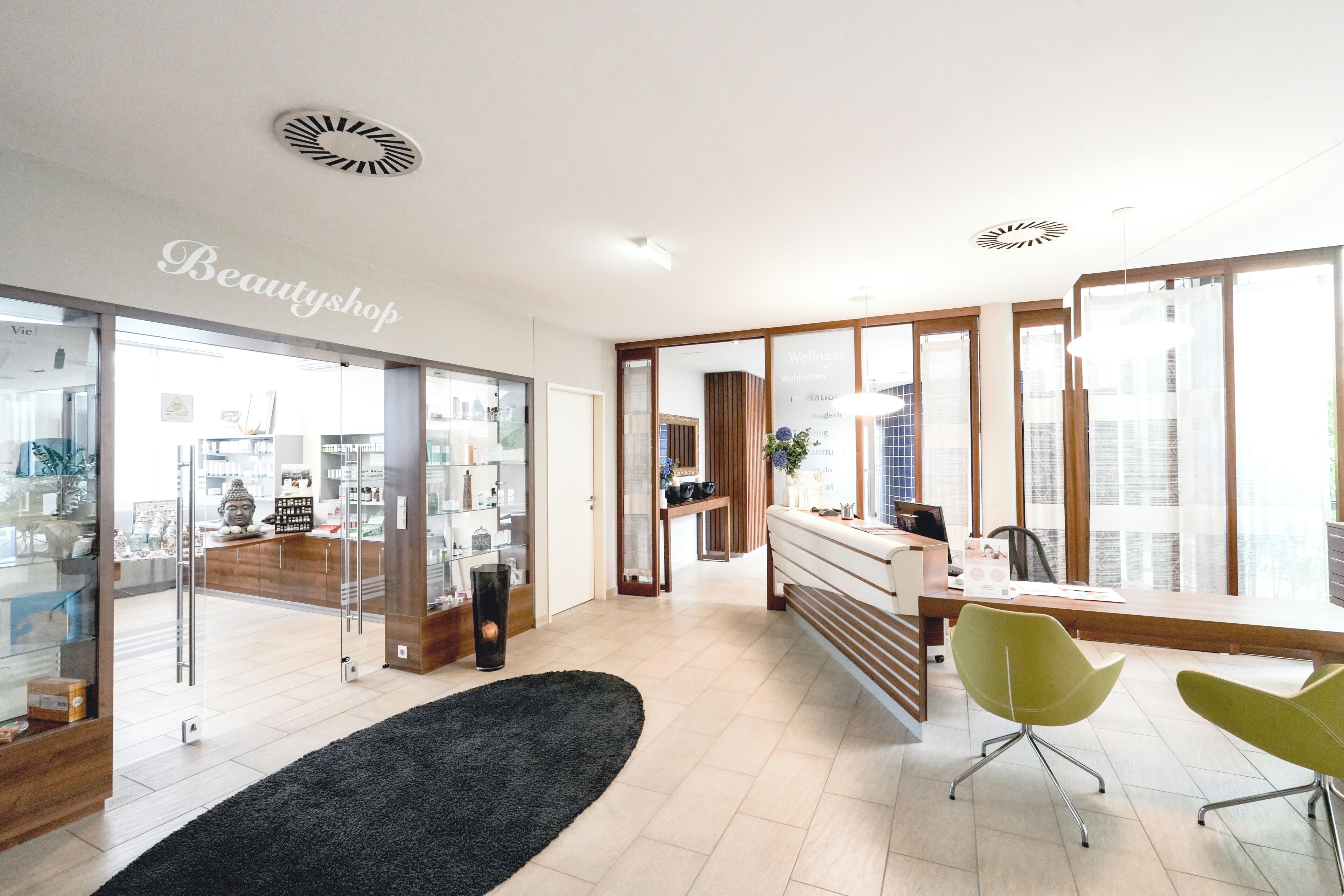 Un interior moderno con mostrador de recepción, una silla verde y un tapete negro.