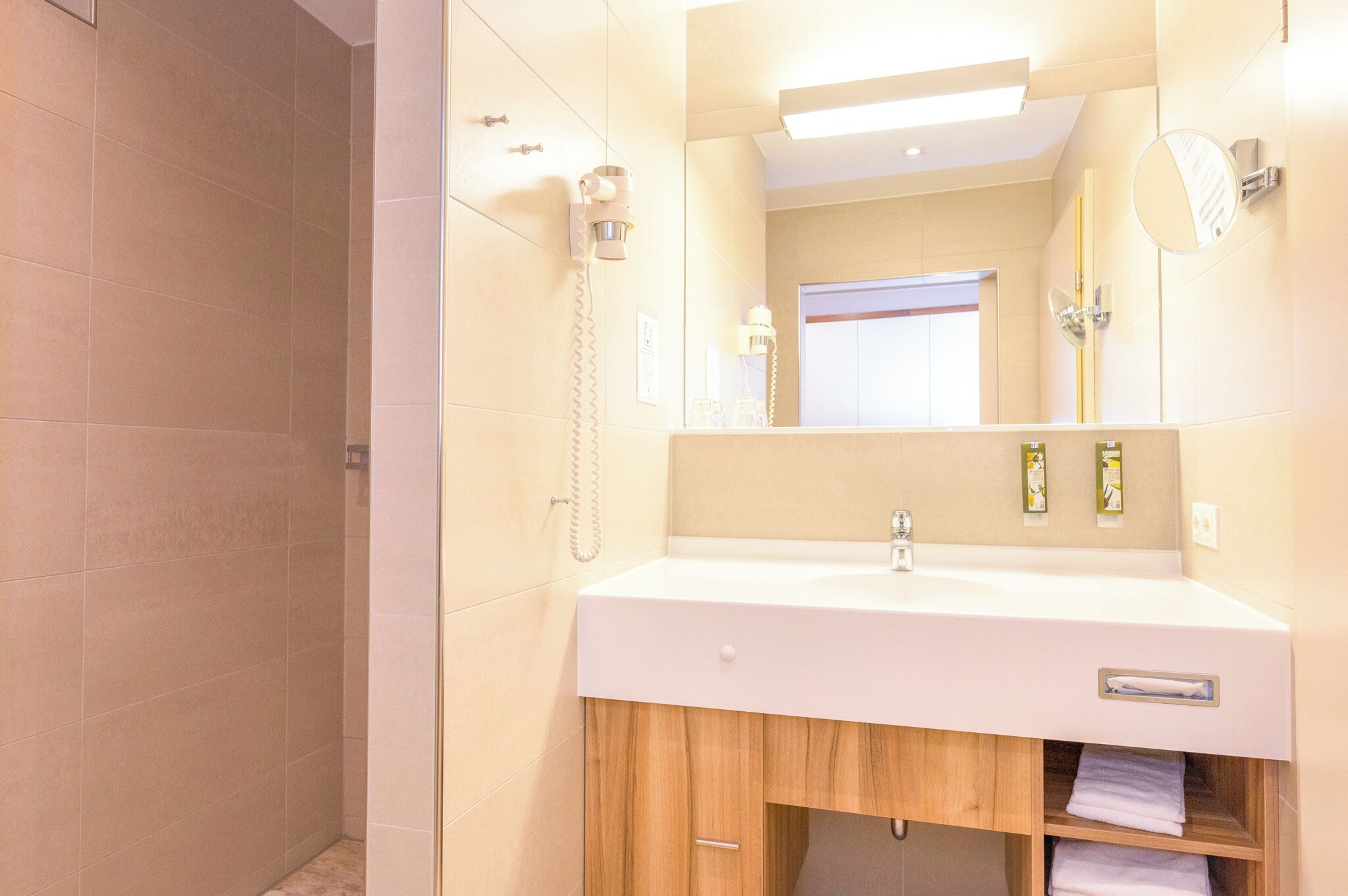 A bathroom with a white sink, wooden cabinet, and a mirror.