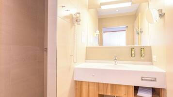 A bathroom with a white sink, wooden cabinet, and a mirror.