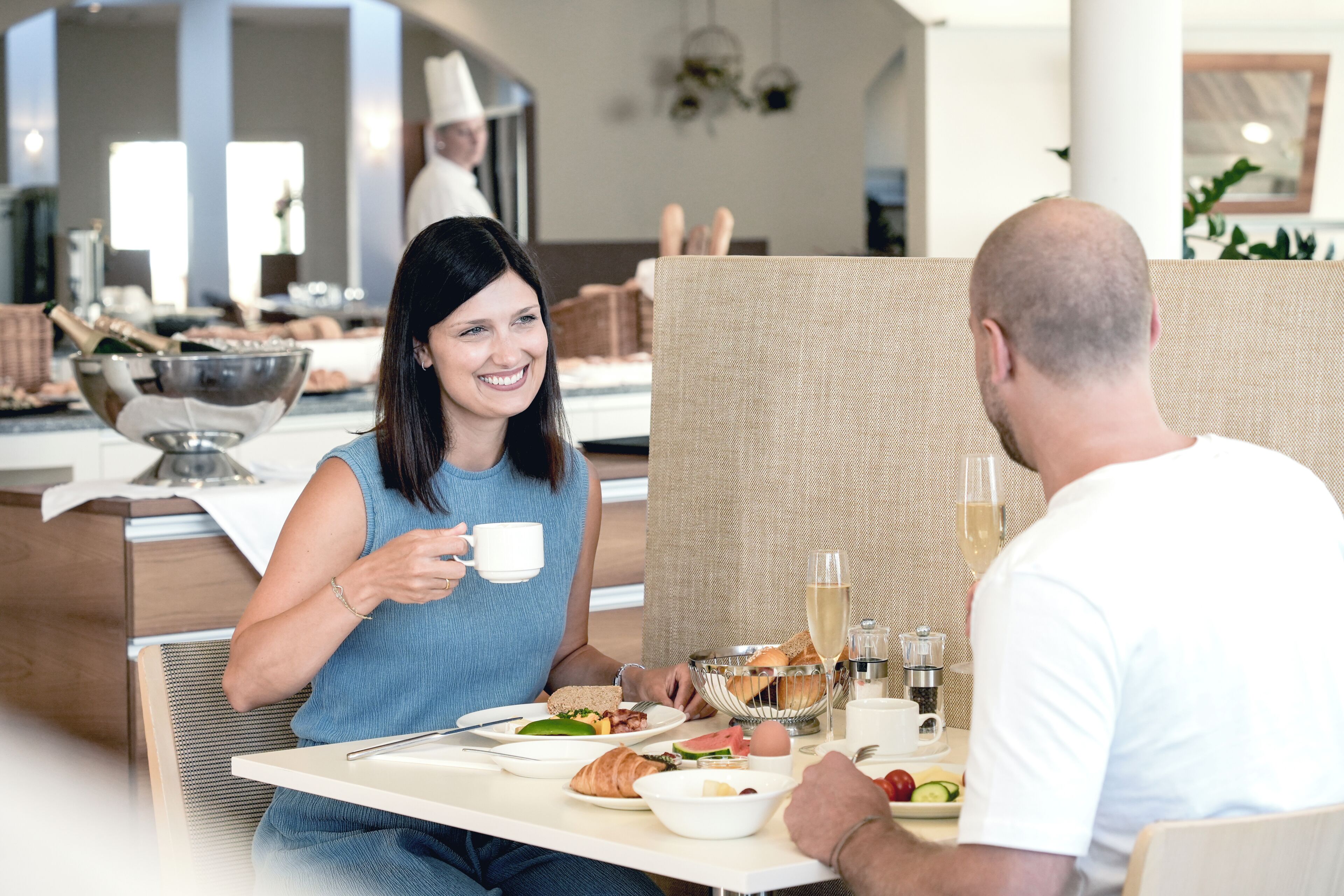 Een modern eetgedeelte met een hoge tafel, diverse soorten eten en een glas champagne.