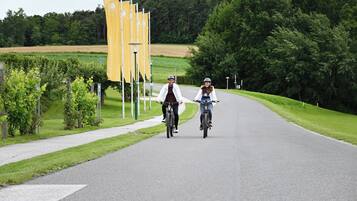 Dos personas montando en bicicleta por una carretera pavimentada, con vegetación a ambos lados.
