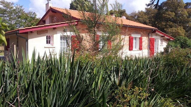 A white building with red shutters and a red roof, surrounded by greenery. - DOMAINE DU FLAMAND - Gîte JUNCA  (Naujac-sur-Mer)