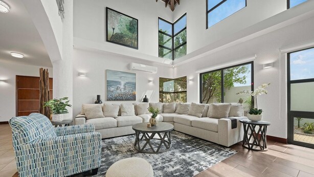 A spacious living room with a sectional sofa, a patterned armchair, and a round coffee table. - Lux Villa Oasis: 5BR w Pool* Playground near Beach (Noord)