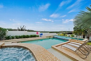 Une piscine avec un jacuzzi, des chaises longues et une vue sur le paysage.
