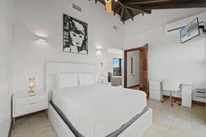 Ein Schlafzimmer mit einem großen Bett, Nachttischen, einem Schreibtisch und einem Sessel.