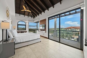 Una camera da letto con un letto, una scrivania, una TV e un balcone con vista.