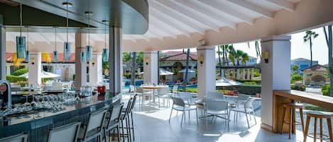 Ein moderner Außenbereich mit Bar, Poolblick, Barhocker und Sitzgelegenheiten.