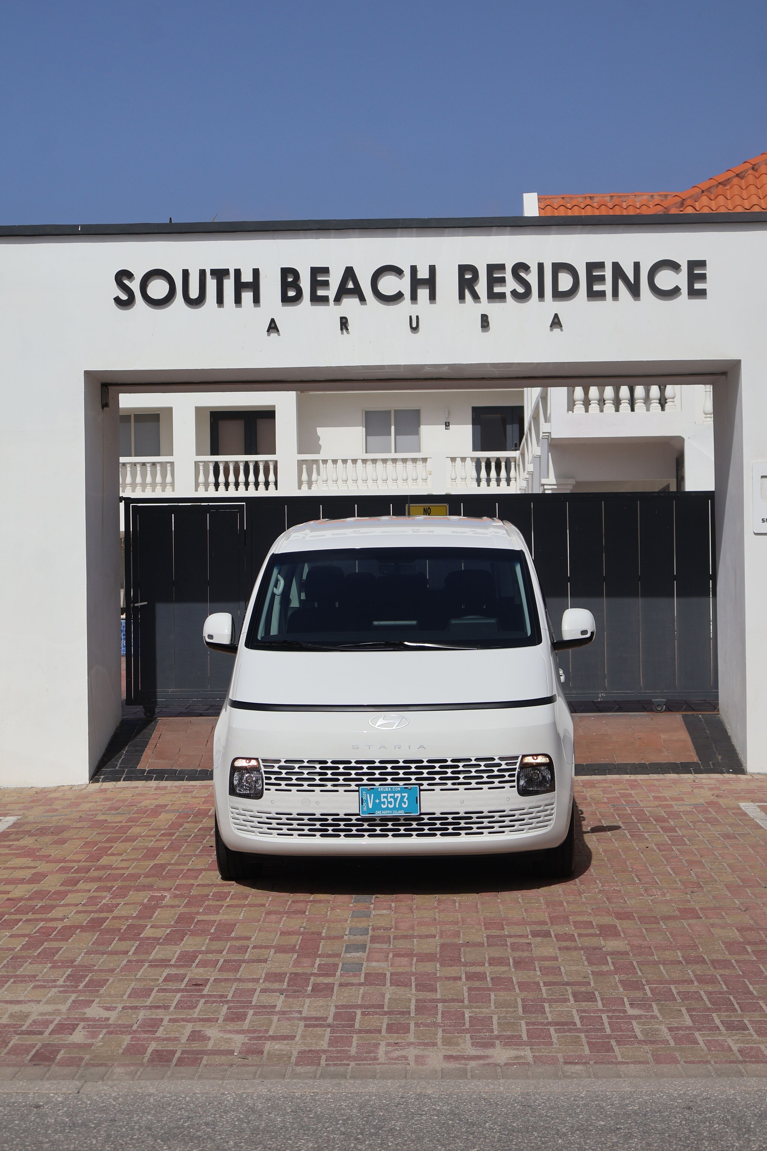 A white Mercedes-Benz Sprinter van parked in front of a building labeled 'South Beach Residence Aruba.'