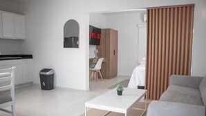 Una sala de estar moderna con un sofá blanco, una mesa de centro y un televisor montado en la pared.
