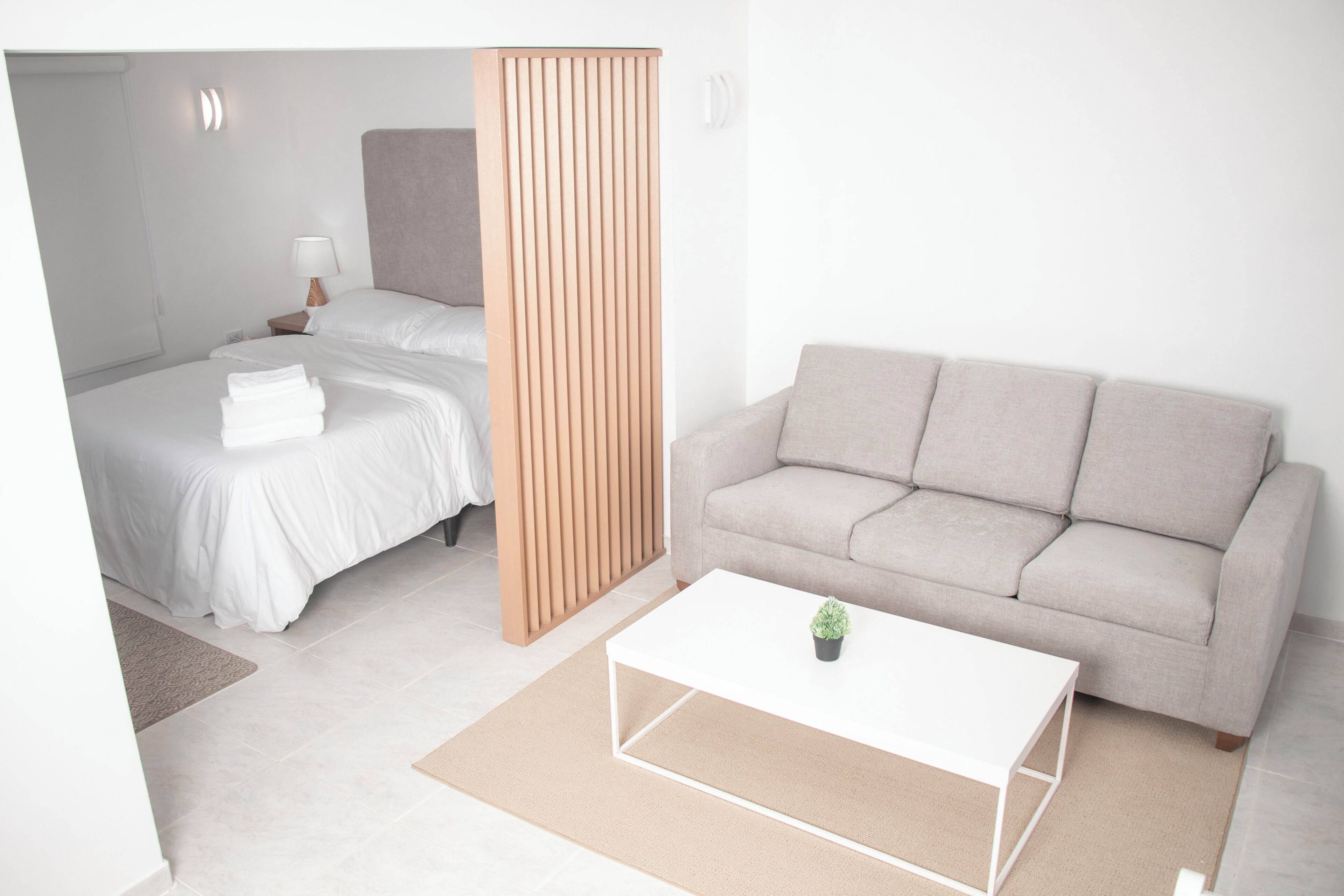 Ein modernes Hotelzimmer mit einem Bett, einer Couch, einem Couchtisch und einer Holzwand.